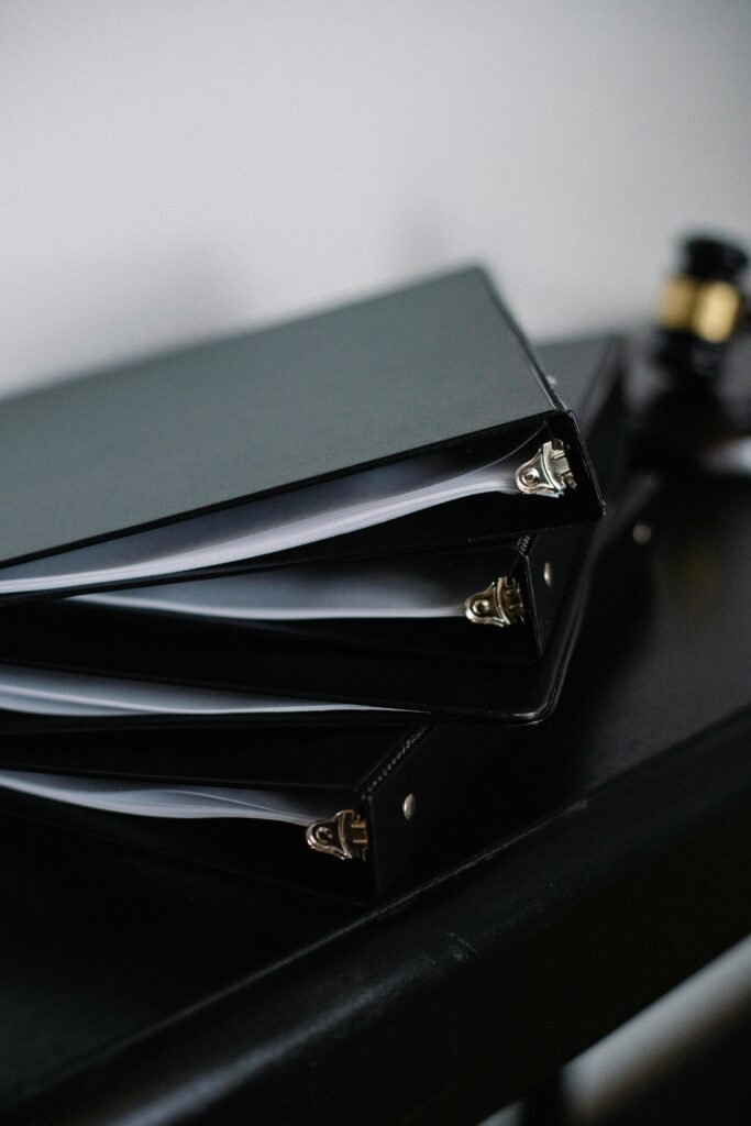 Close-up of neatly stacked black office binders on a desk, symbolizing organization.